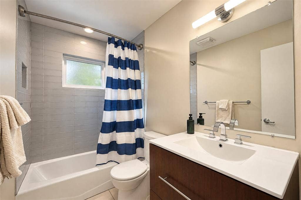 6866 Burwood Lane, Dallas, TX 75214 Bathroom featuring a wood-finish vanity with an integrated sink, polished chrome faucet, and a large wall mirror
