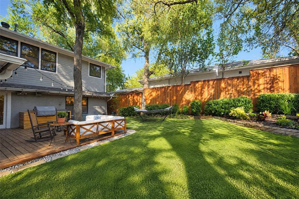 6866 Burwood Lane, Dallas, TX 75214 Expansive green lawn, wood privacy fencing, a wood-finish deck, and mature trees