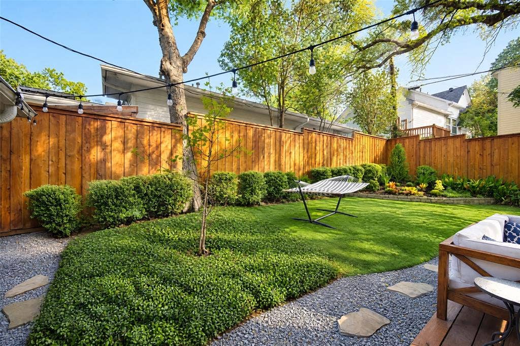 6866 Burwood Lane, Dallas, TX 75214 Fenced backyard featuring natural wood fencing, a manicured lawn, established landscaping, and a gravel path with stepping stones