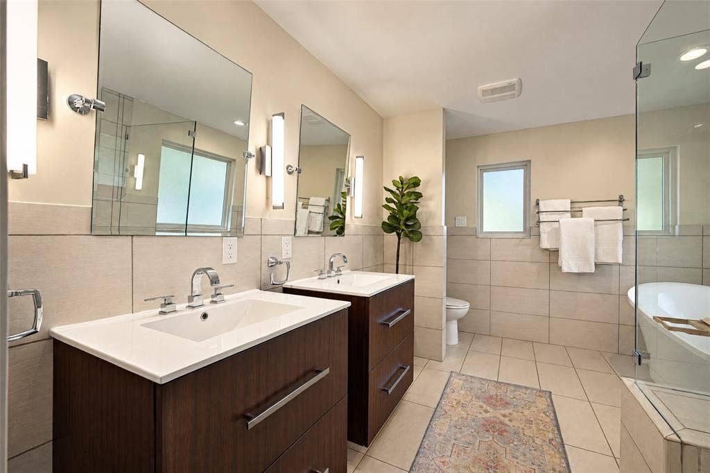 6866 Burwood Lane, Dallas, TX 75214 Dual vanity with wood-finish cabinetry, white countertops, and undermount sinks