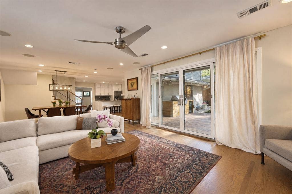 6866 Burwood Lane, Dallas, TX 75214 Open-concept living area featuring wood-finish flooring, a contemporary ceiling fan, recessed lighting, and sliding glass doors leading to an outdoor space