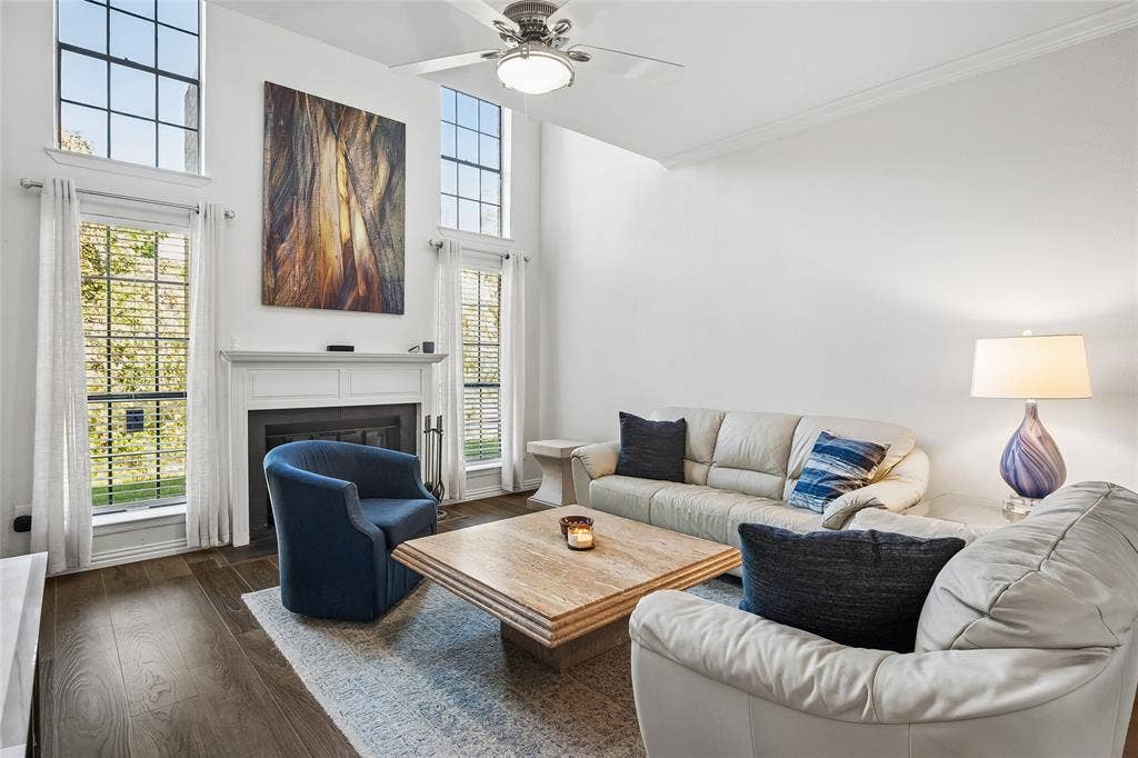 Vaulted ceilings, floor-to-ceiling windows, wood-finish flooring, and a fireplace with a custom mantel
