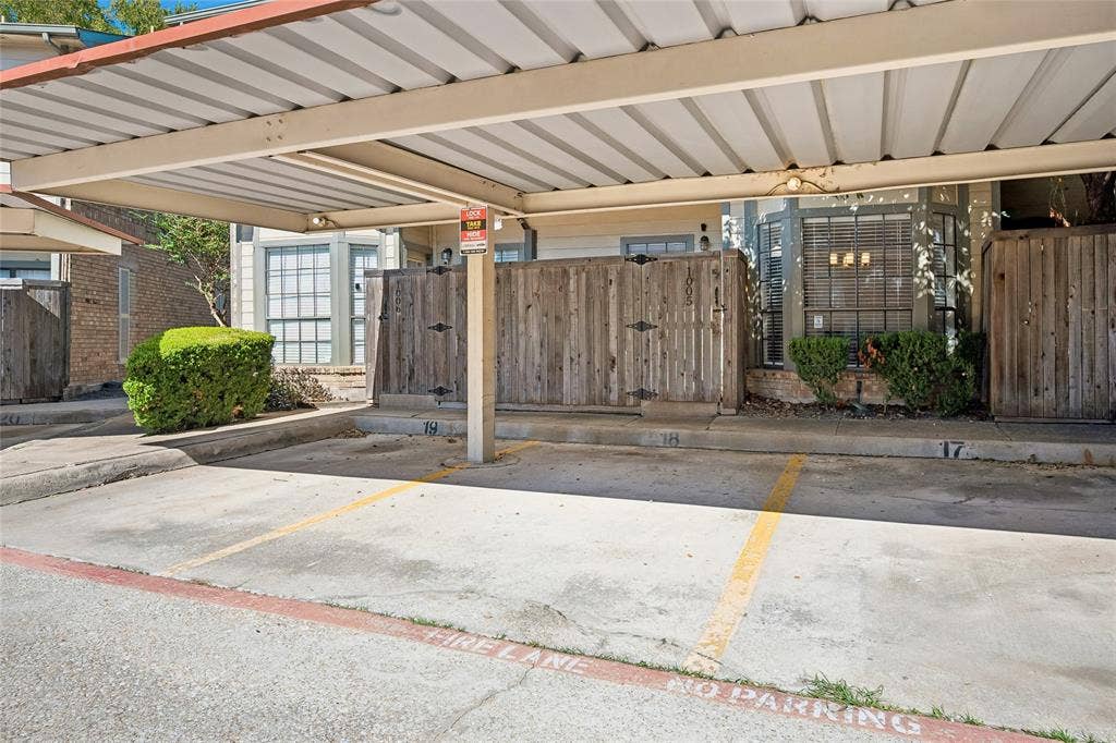 Covered parking structure with designated spaces, concrete surface, and wood privacy fencing