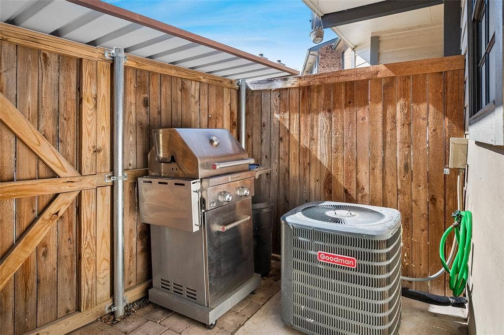 Outdoor service area featuring a horizontal wood privacy fence, a corrugated metal awning, and concrete paver flooring