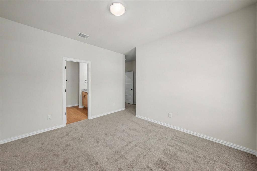 Neutral wall color, wall-to-wall carpeting, flush-mount ceiling light, and an open doorway