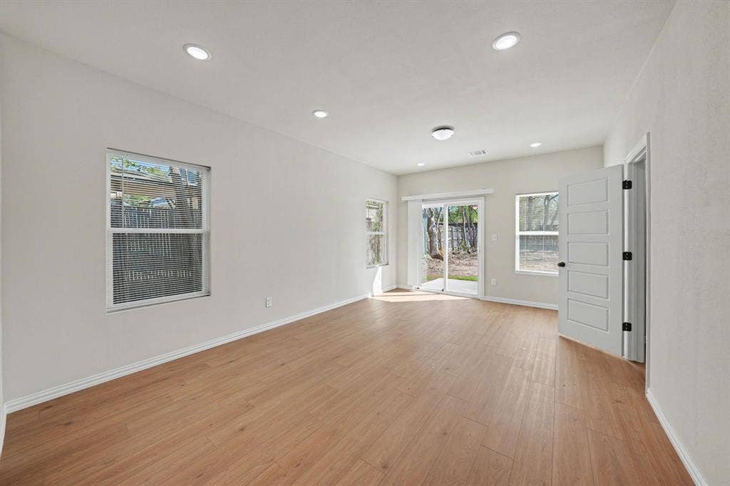 Spacious room featuring wood-finish flooring, recessed lighting, and multiple windows
