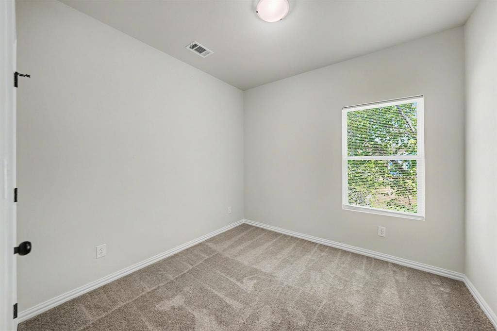 Light gray wall paint, textured carpet flooring, single window, white trim, flush mount ceiling light