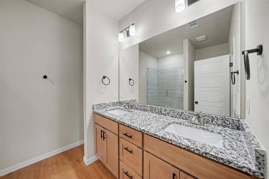 Double vanity with wood-finish cabinetry, speckled countertops, and undermount sinks