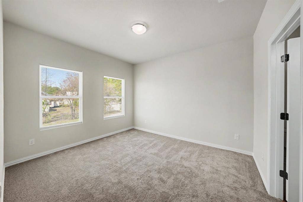 Neutral wall color, carpet flooring, two windows, and an overhead flush-mount light fixture