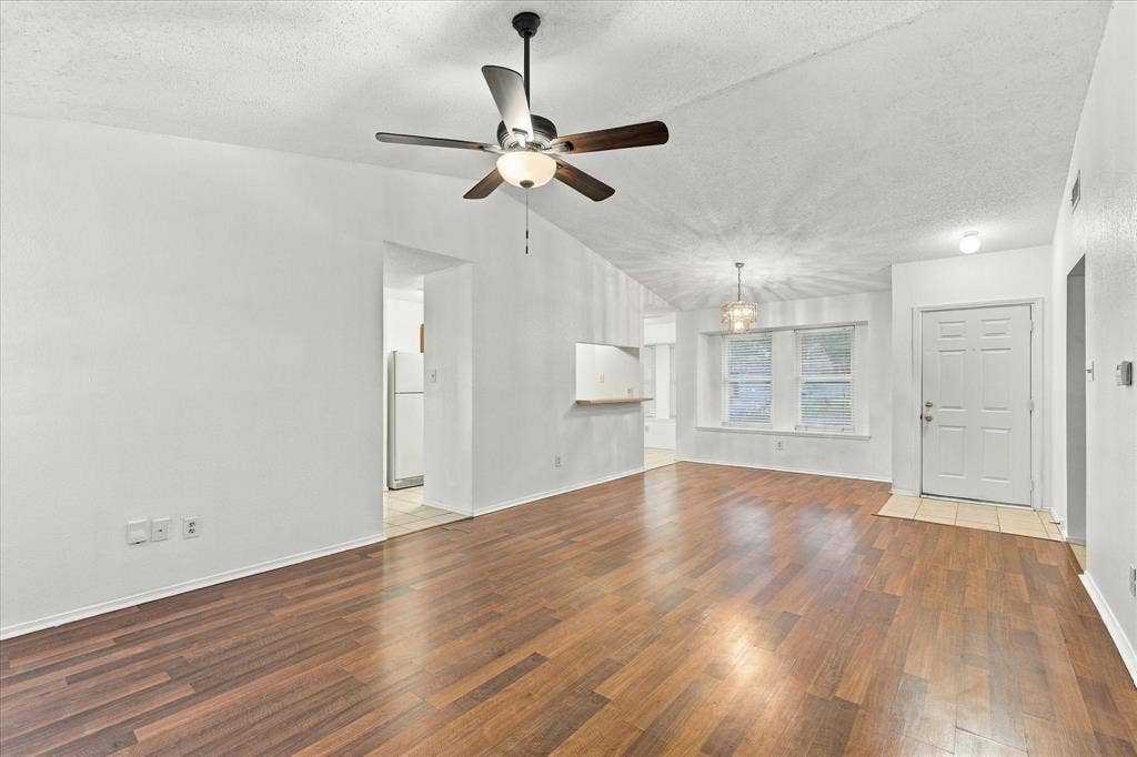 844 Woodrock Drive, Dallas, TX 75217 Wood-finish flooring throughout, vaulted ceiling, built-in ceiling fan, white paneled entry door, and multiple windows with white trim