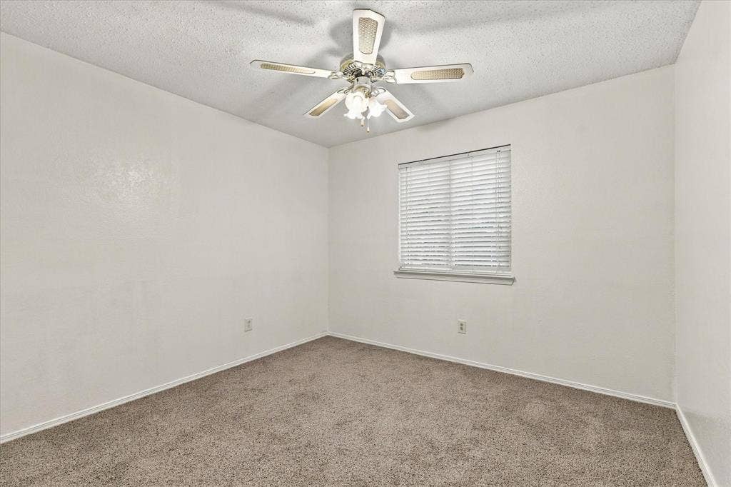 844 Woodrock Drive, Dallas, TX 75217 Neutral carpeted flooring, white painted walls, a window with horizontal blinds, and a ceiling fan with integrated lighting
