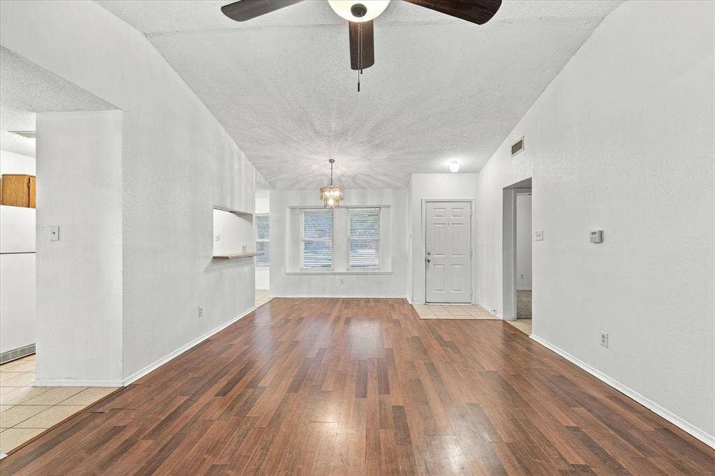 844 Woodrock Drive, Dallas, TX 75217 Vaulted ceilings, wood-finish flooring, two windows, and a pass-through opening to the kitchen
