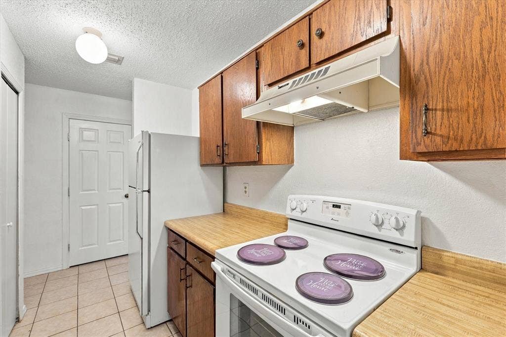 844 Woodrock Drive, Dallas, TX 75217 Kitchen featuring wood-finish cabinetry, laminate countertops, and tile flooring
