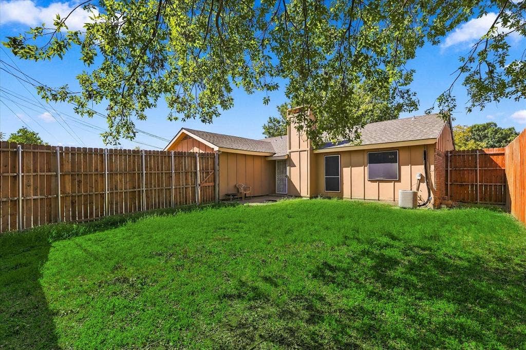 844 Woodrock Drive, Dallas, TX 75217 Expansive backyard featuring a lush lawn, privacy fencing, and mature trees