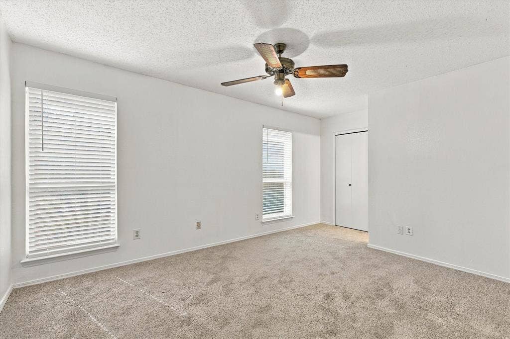 844 Woodrock Drive, Dallas, TX 75217 Carpeted room featuring two windows with horizontal blinds, a ceiling fan with light fixture, and a built-in closet with bifold doors