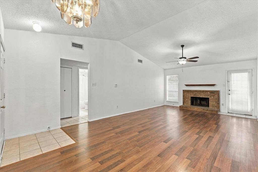 844 Woodrock Drive, Dallas, TX 75217 Vaulted ceiling with a ceiling fan, wood-finish flooring, brick-surround fireplace with a wood mantel, and an exterior door