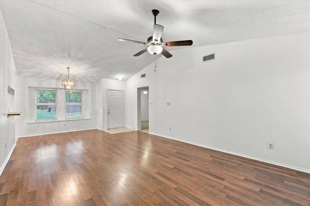 844 Woodrock Drive, Dallas, TX 75217 Vaulted ceiling with a ceiling fan, recessed lighting, wood-finish flooring, white walls, and a decorative chandelier