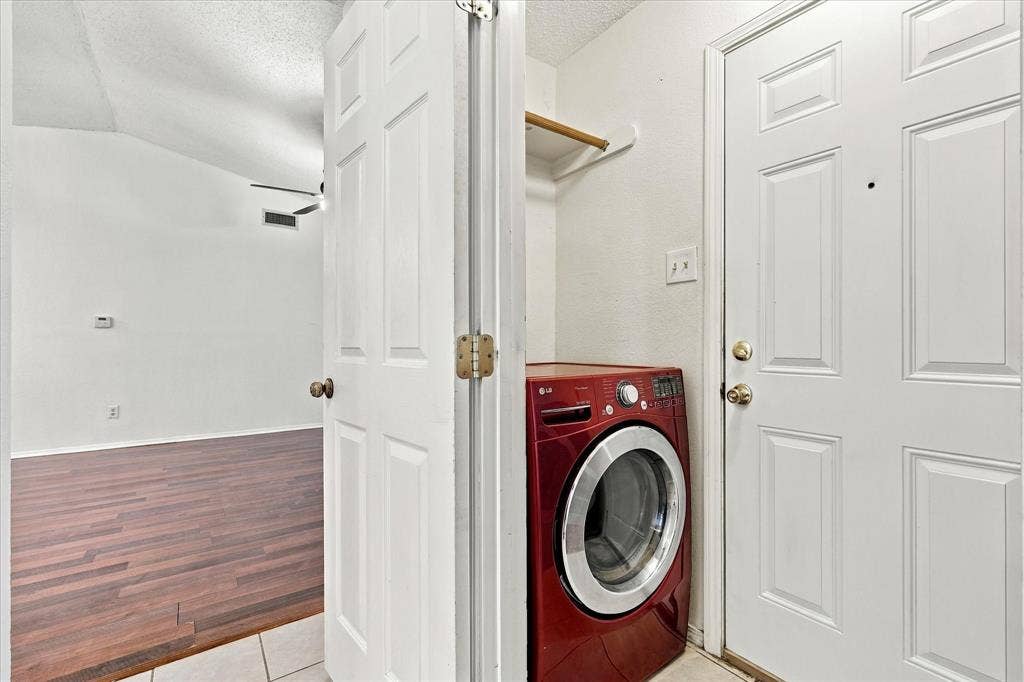 844 Woodrock Drive, Dallas, TX 75217 Dedicated laundry area with a built-in shelf, adjacent to a room with wood-finish flooring and a vaulted ceiling