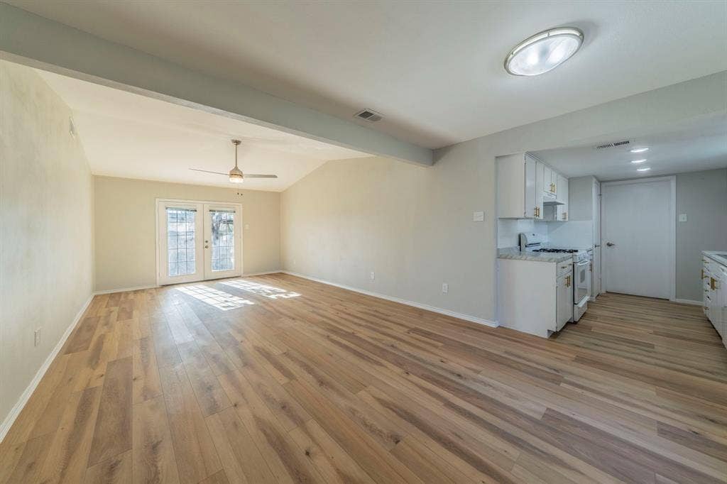 802 Birchwood Drive, Garland, TX 75043 Vaulted ceiling, wood-finish flooring, ceiling fan, white kitchen cabinetry, and granite countertops