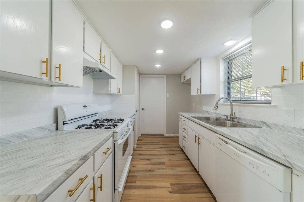 802 Birchwood Drive, Garland, TX 75043 Kitchen featuring white cabinetry with gold-toned hardware, stone-look countertops, white subway tile backsplash, and wood-finish flooring