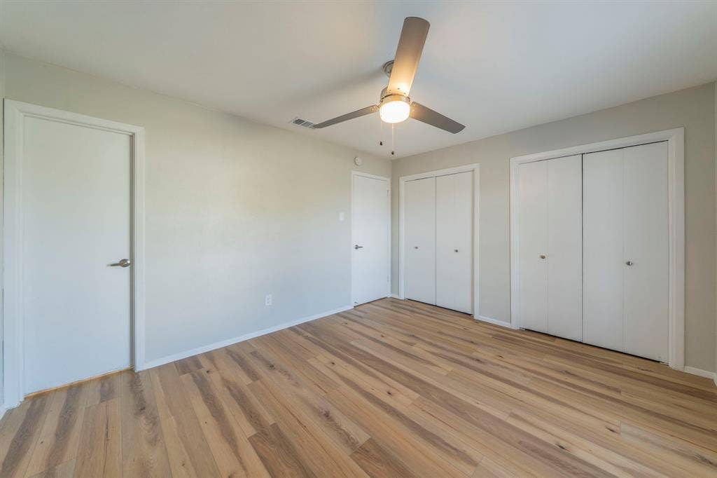 802 Birchwood Drive, Garland, TX 75043 Light wood-finish flooring, neutral wall tones, modern ceiling fan with integrated lighting, and multiple closet storage options