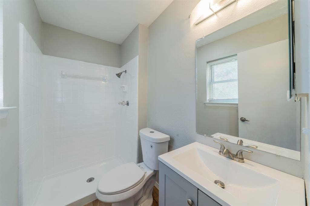 802 Birchwood Drive, Garland, TX 75043 Modern bathroom featuring a single vanity with a gray cabinet, an integrated sink, and brushed nickel fixtures