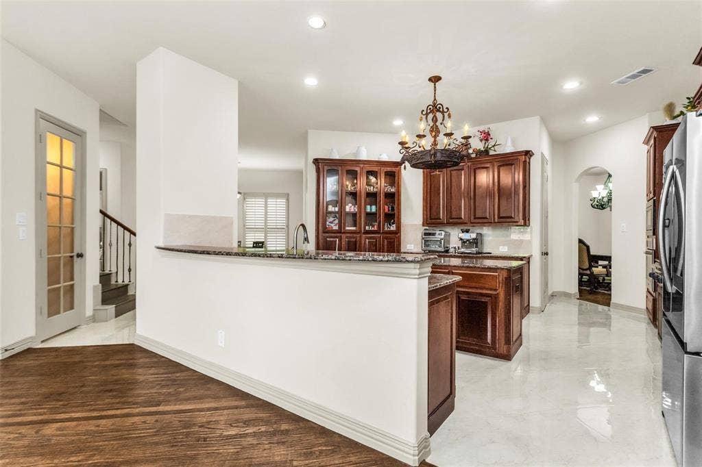 1838 Olney Drive, Allen, TX 75013 Kitchen featuring wood cabinetry, stainless steel appliances, granite countertops, and a decorative chandelier