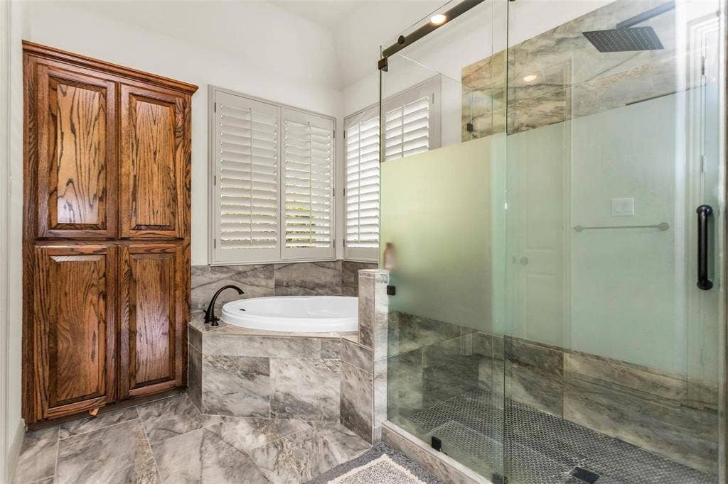1838 Olney Drive, Allen, TX 75013 Built-in wood cabinetry, a deep soaking tub, plantation shutters, a glass-enclosed shower with a rain shower head, and stone-finish tile flooring