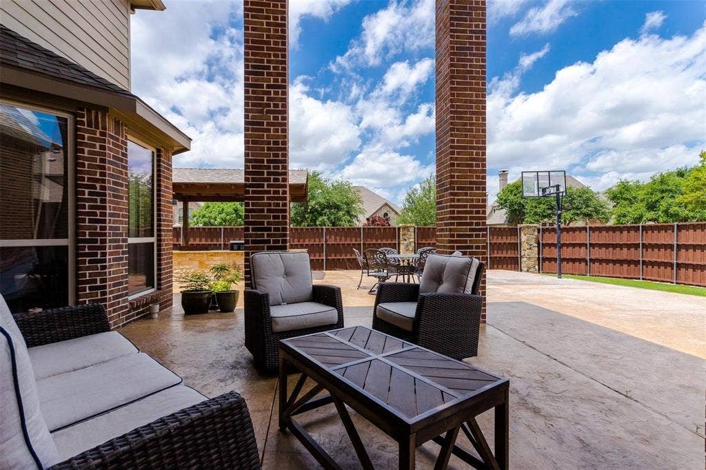 1838 Olney Drive, Allen, TX 75013 Expansive stamped concrete patio with brick support columns, surrounded by a wood privacy fence