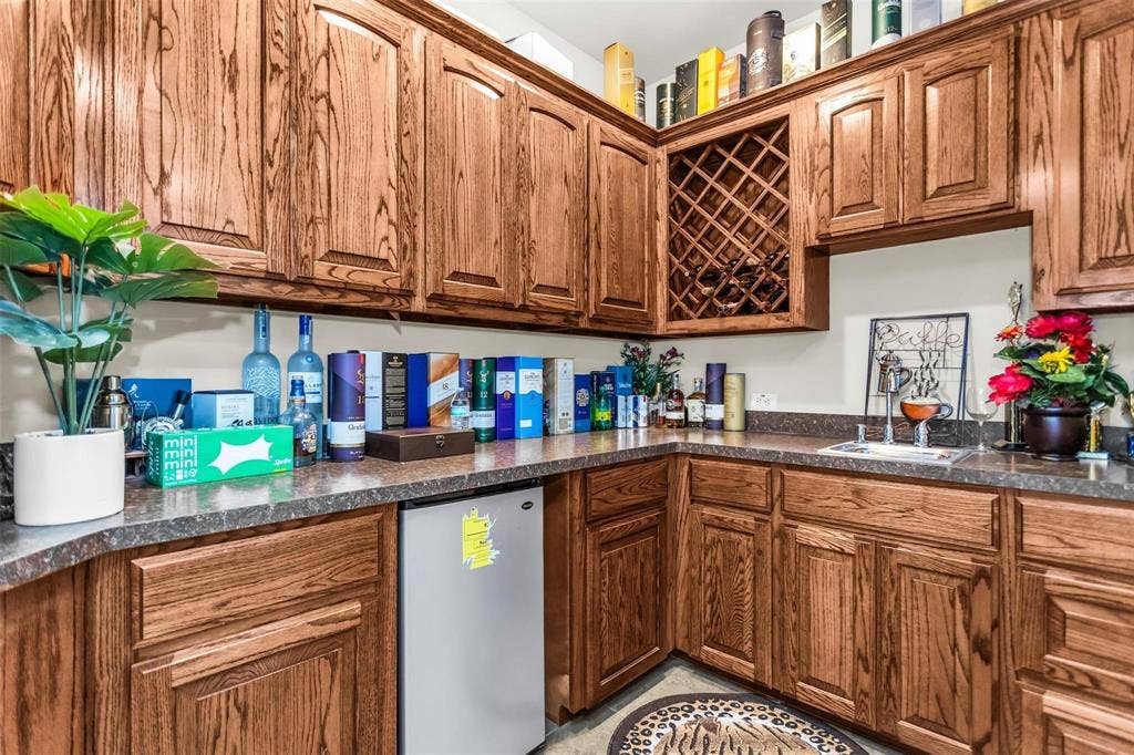 1838 Olney Drive, Allen, TX 75013 Wood-finish cabinetry with integrated wine storage, patterned countertops, and a built-in beverage refrigerator