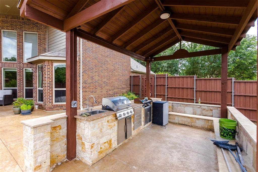 1838 Olney Drive, Allen, TX 75013 Covered outdoor kitchen featuring a built-in grill, sink, and stone-clad cabinetry