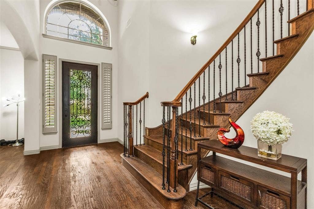 1838 Olney Drive, Allen, TX 75013 Double-height entry with an arched transom window, dark wood-finish flooring, and a wrought iron and wood staircase