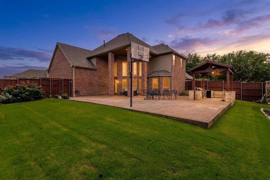 1838 Olney Drive, Allen, TX 75013 Expansive backyard featuring a large concrete patio, brick exterior, and a built-in outdoor kitchen with a wooden pergola