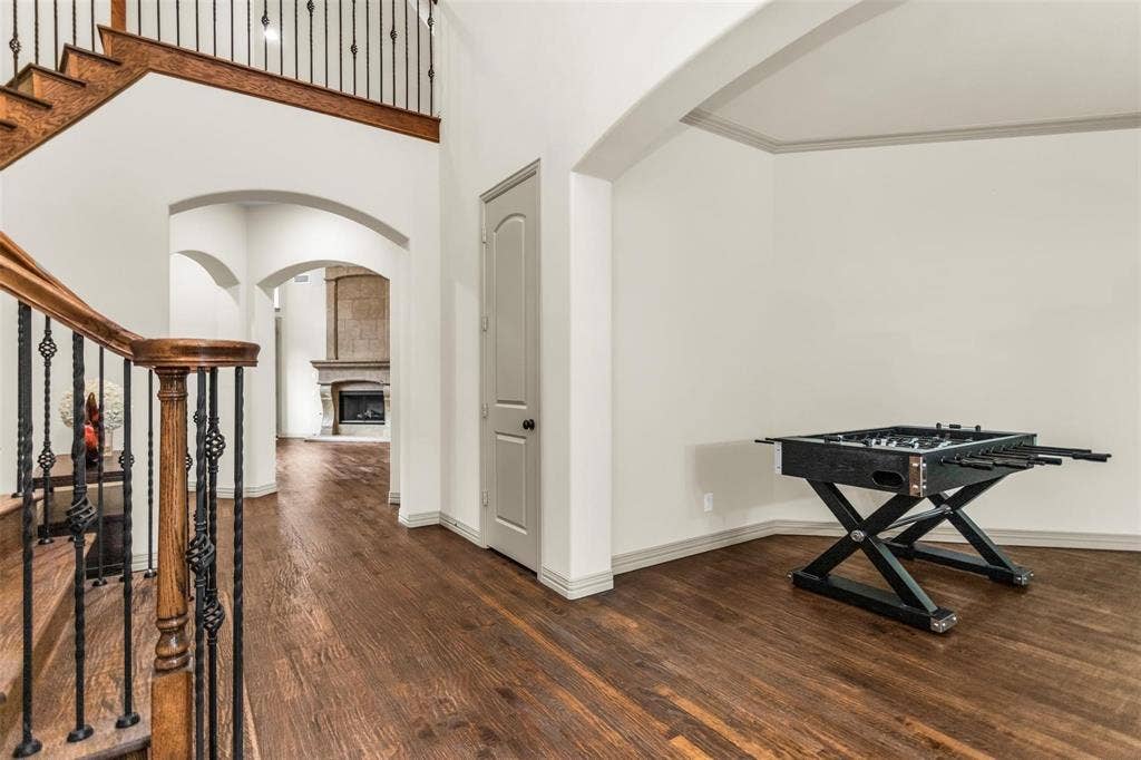 1838 Olney Drive, Allen, TX 75013 Hardwood flooring throughout, arched doorways, wrought iron stair balusters, and a stone-clad fireplace