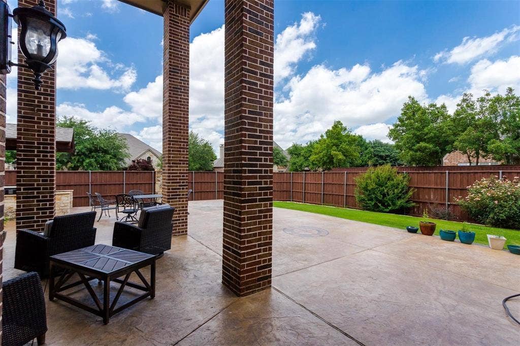 1838 Olney Drive, Allen, TX 75013 Covered patio featuring brick columns, stamped concrete flooring, and a manicured lawn area with a wood privacy fence