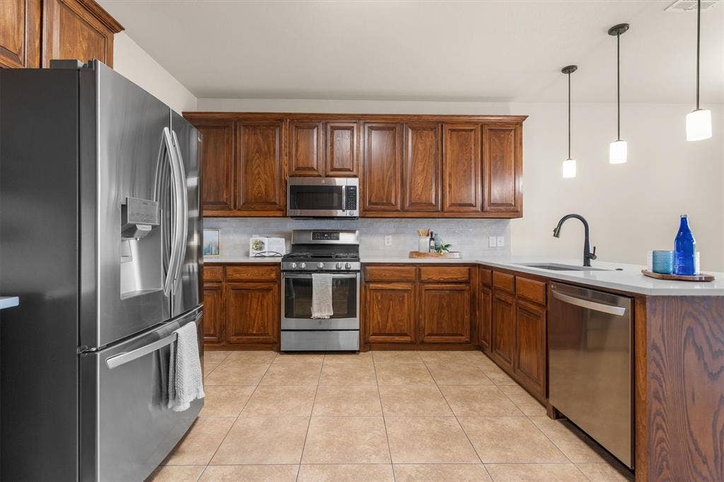 Well-appointed kitchen with stainless refrigerator, dishwasher, and abundant cabinetry