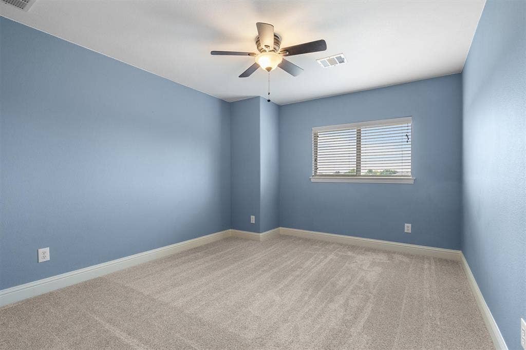 Secondary bedroom with ceiling fan and window views