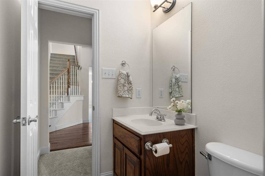 Full bathroom with vanity, mirror, and easy access to the staircase and living areas