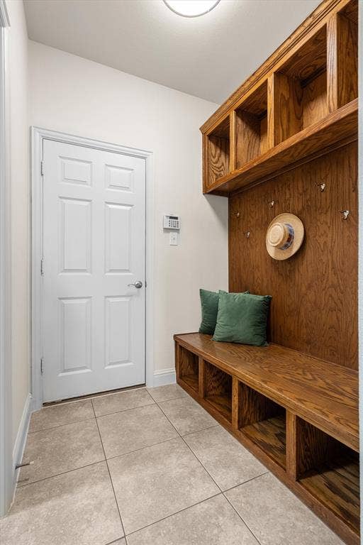 Practical mudroom with bench seating, hooks, and tile flooring