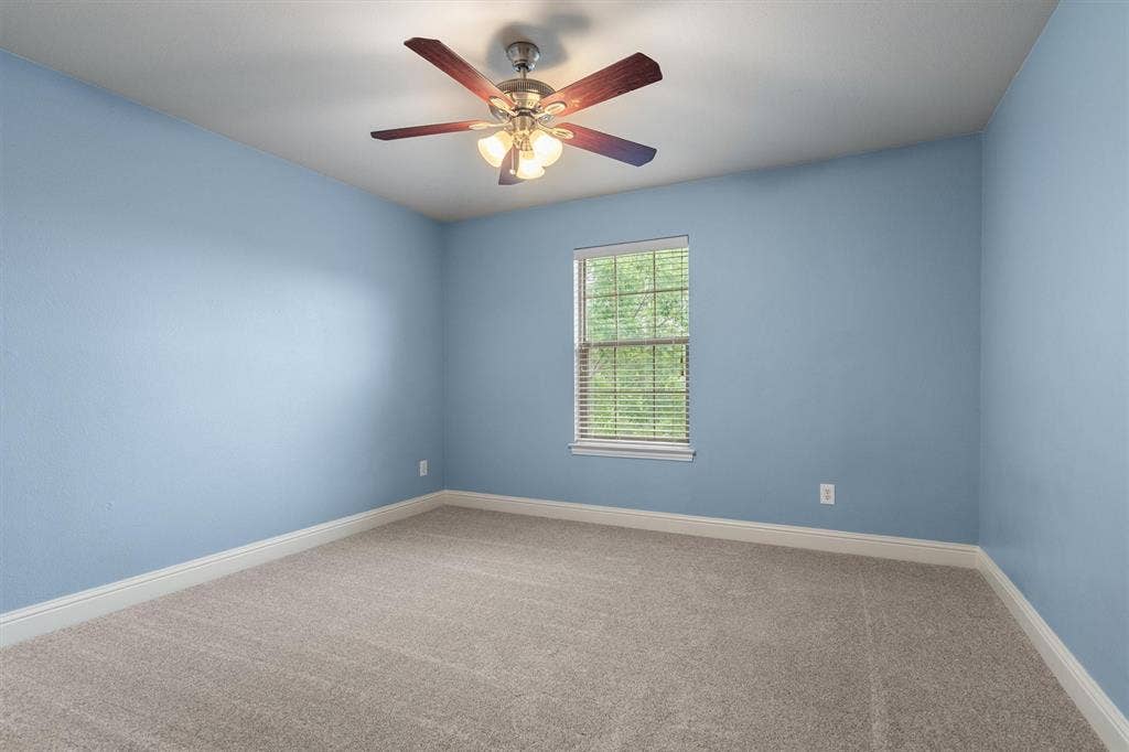 Spacious bedroom with ceiling fan and natural light