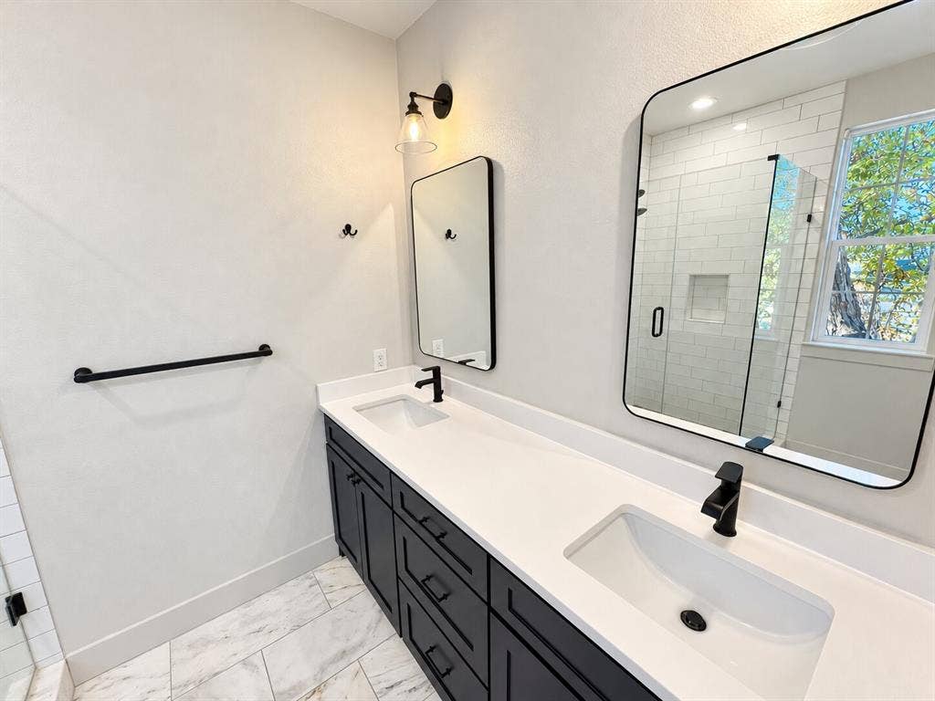 Modern primary bathroom featuring a dual-sink vanity with white quartz countertop, matte black hardware and faucets, and an undermount basin design