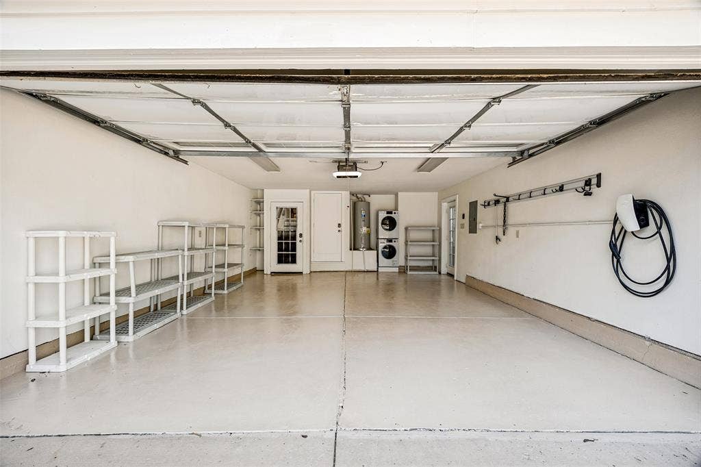 320 E 5th Street, Dallas, TX 75203 Garage featuring an epoxy floor, built-in shelving, laundry appliances, a water heater, and an EV charging station