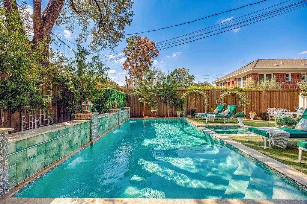 320 E 5th Street, Dallas, TX 75203 Swimming pool with integrated spa, waterfall feature, artificial turf surround, and wooden privacy fencing