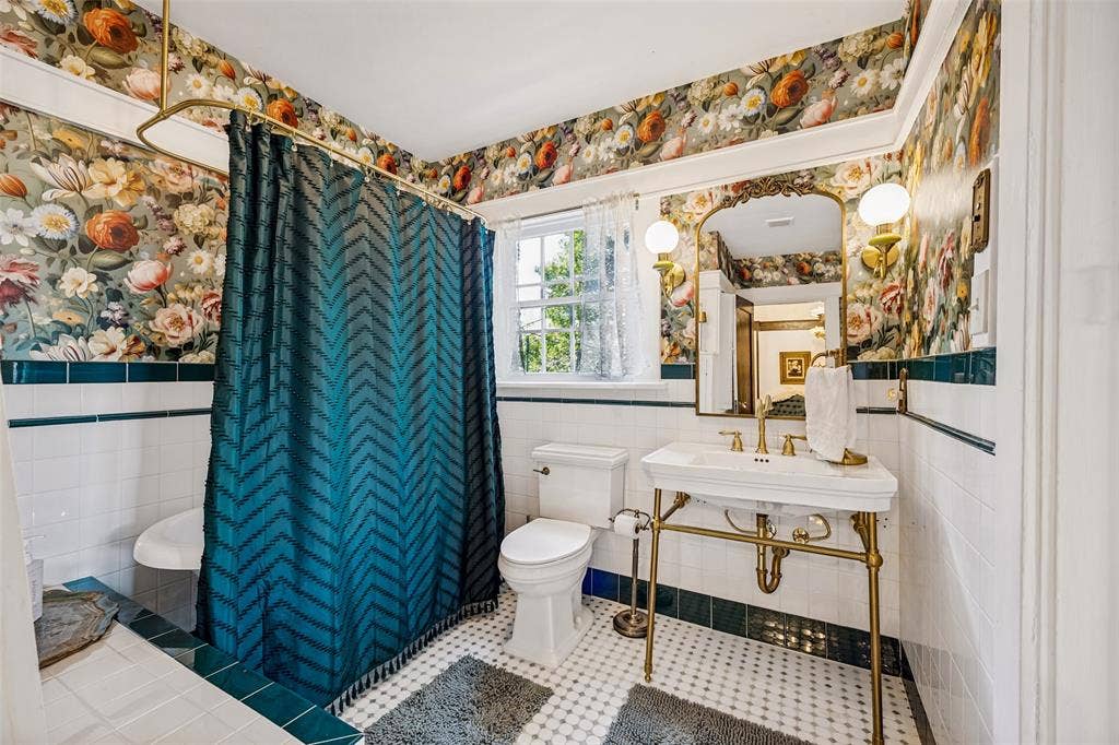 320 E 5th Street, Dallas, TX 75203 Pedestal sink with brass-finish legs and fixtures, ornate framed mirror with sconce lighting, and patterned wallpaper