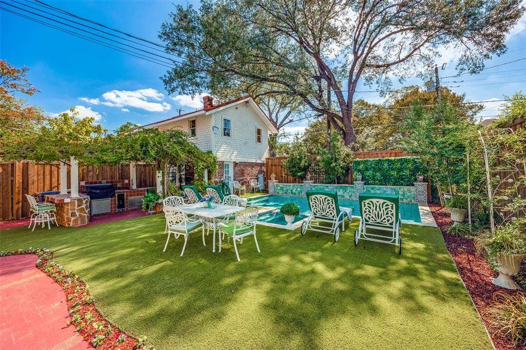 320 E 5th Street, Dallas, TX 75203 Outdoor entertaining area with artificial turf, an integrated outdoor kitchen, a swimming pool with decorative tile, and a privacy fence