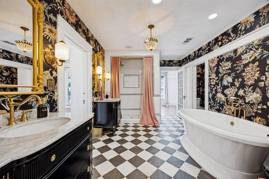 320 E 5th Street, Dallas, TX 75203 Black and white checkered tile flooring, ornate gold-framed mirrors, free-standing soaking tub, built-in vanity with marble countertop, and a glass-enclosed shower