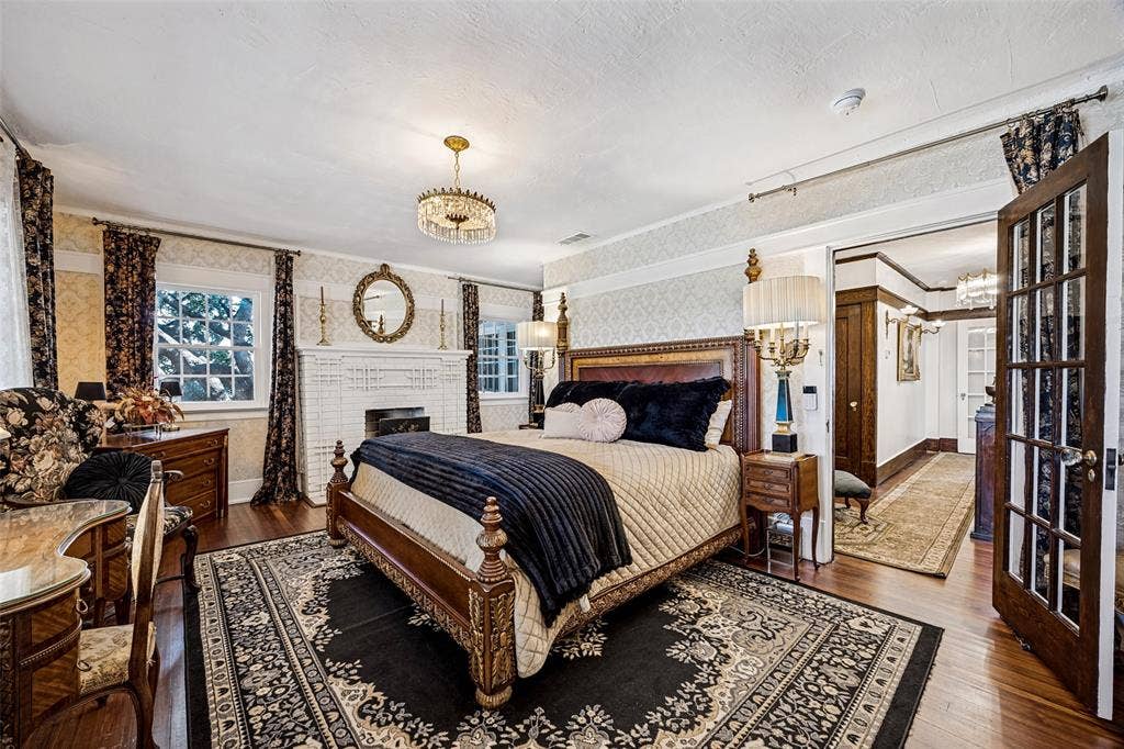 320 E 5th Street, Dallas, TX 75203 Hardwood flooring, decorative fireplace, crystal chandelier, double french doors, and patterned wallpaper