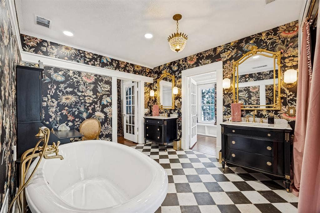 320 E 5th Street, Dallas, TX 75203 Freestanding soaking tub with a brass fixture, dual vanity sinks with marble tops, ornate gold-framed mirrors, and checkerboard floor tiling