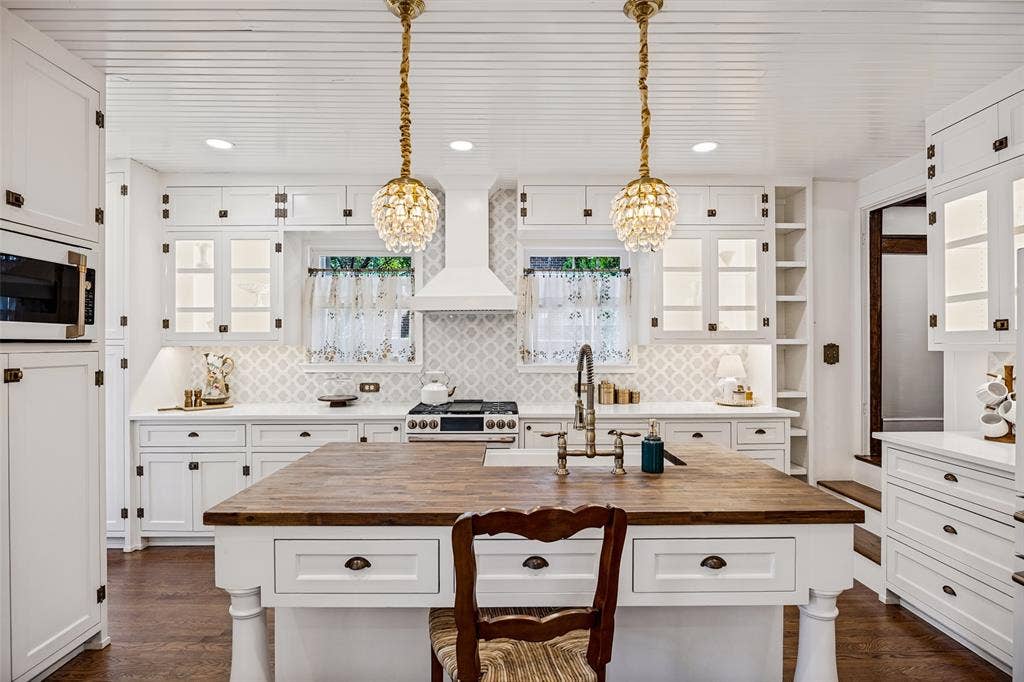 320 E 5th Street, Dallas, TX 75203 Spacious kitchen with a central wood-finish island, white cabinetry, integrated microwave, and a decorative tile backsplash