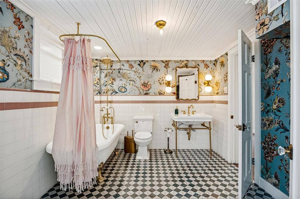 320 E 5th Street, Dallas, TX 75203 Clawfoot bathtub with brass fixtures, pedestal sink with brass frame, patterned floor tiles, shiplap ceiling, and ornamental wall coverings